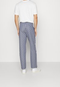 Blå mönstrade byxor med en diamantdesign och vita sidstrimlor. Tillverkade av ett andningsbart material, med en avslappnad passform och elastisk midja.