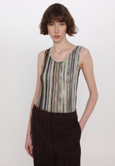 Strappy bodysuit with multicolored vertical stripes, made of a textured knit material. Paired with dark burgundy, zigzag-patterned pants.