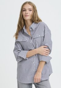Striped button-up shirt in navy and white, featuring two chest pockets, long sleeves, and a relaxed fit, made of lightweight fabric.