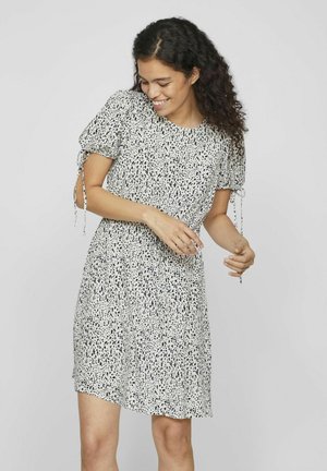 Vestido estampado en blanco y negro con mangas cortas abullonadas, lazos ajustables en las mangas y un diseño fluido. Tela ligera con un corte holgado.