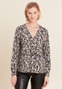 Langarmblouse met een zwart-wit bloemenpatroon en oranje accenten, een v-halslijn en knoopsluiting aan de voorkant.