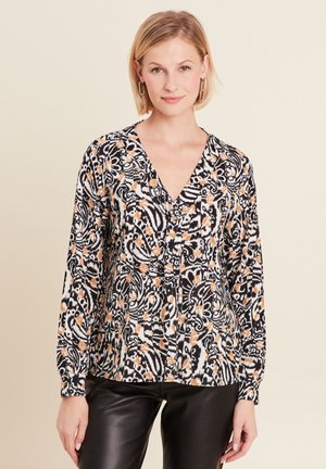 Langarmblouse met een zwart-wit bloemenpatroon en oranje accenten, een v-halslijn en knoopsluiting aan de voorkant.