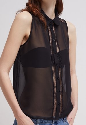 Blusa nera trasparente senza maniche con colletto, caratterizzata da un pannello in pizzo lungo il centro, chiusura con bottoni e tessuto morbido e drappeggiato.