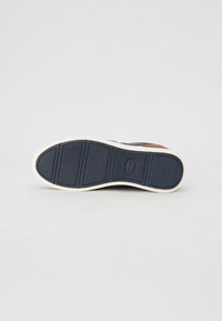 Sko soles med gummimateriale, marineblå farge, teksturert overflate og flere riller for grep. Har en hvit mellomsåle.