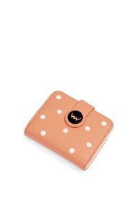 Peach-colored leather wallet with large white polka dots, rounded shape, magnetic closure, and a black circular logo accent.