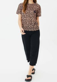 Tričko s leopardím potiskem v růžové a hnědé barvě, s krátkými rukávy a náprsní kapsou, doplněné černými krátkými kalhotami a černými sandály.