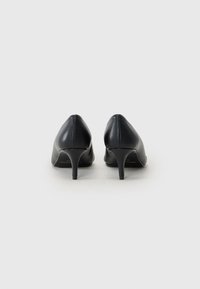 Sorte skinnhøye hæler med spiss tå og slank stiletto hæl. Glatt tekstur og minimal sømdetalj bak.