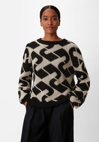 Zwart en crèmekleurig gebreid sweater met een ronde hals, voorzien van gedurfde geometrische vormen en een zachte, textuurrijke stof.