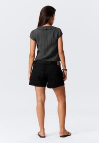 Sorte denimshorts med sidelommer, parret med en textured mørkegrå bluse med en flæsekrave. Minimalistisk design, afslappet pasform.