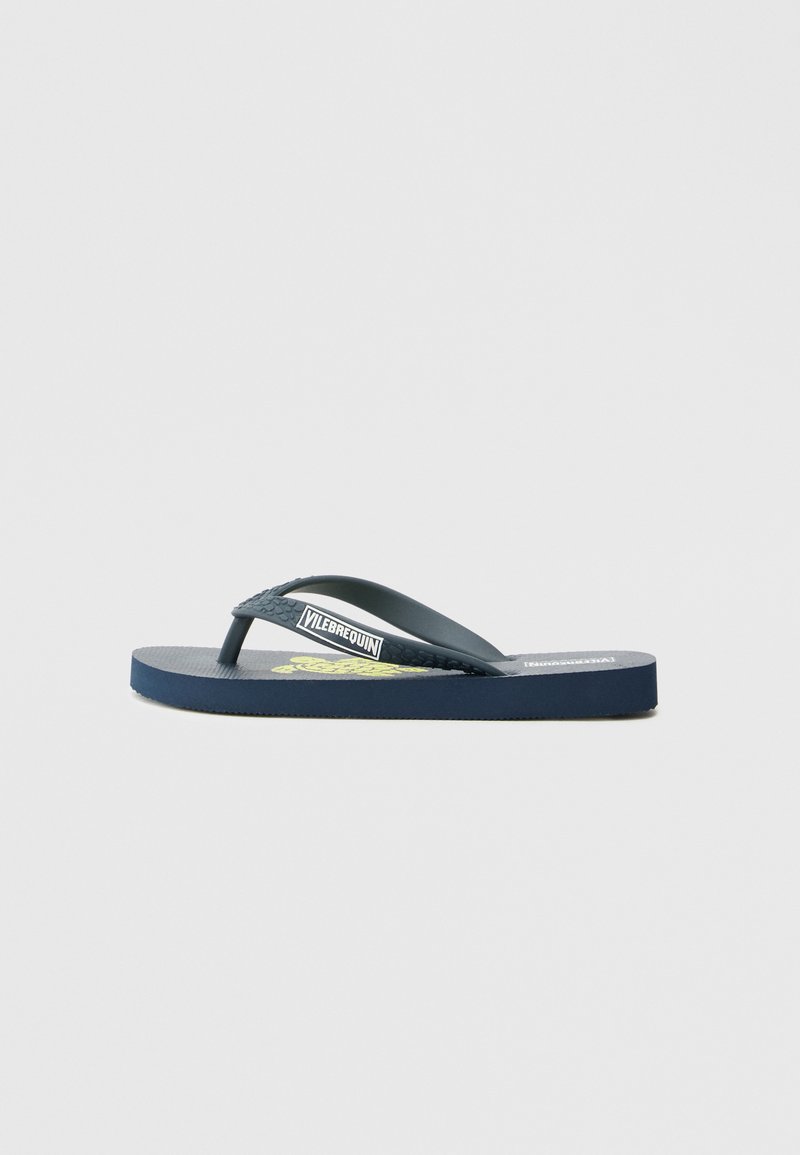 Temno modre gumijaste japonke z teksturiranimi trakovi in rumenim tiskom logotipa na podplatu. Raven podplat z rahlim lokom.