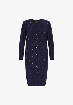 Granatowa sukienka dzianinowa z długimi rękawami, dekoltem w serek, zapięciem na guziki i rozsypanymi białymi kropkami. Wykonana z miękkiej, teksturowanej tkaniny.
