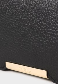 Black textured leather wallet with a gold metal plate featuring the brand name, positioned at the bottom. Smooth edges and compact shape.