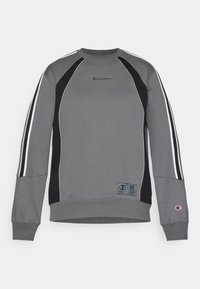 Sudadera gris con acentos negros, rayas laterales blancas y un cuello redondo. Presenta un logo y una etiqueta tejida en el frente.