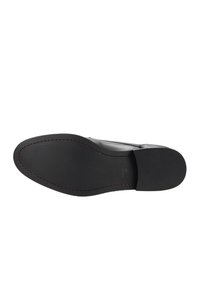 Scarpa in pelle nera con tomaia liscia, punta affilata e suola sottile. Cuciture rosse evidenti lungo il bordo. Design con tacco piatto.