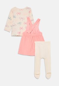 Das dreiteilige Kinderoutfit besteht aus einem cremefarbenen Langarmshirt mit bunten Schleifenmustern, einem rosa Latzkleid und cremefarbenen Strumpfhosen.