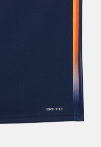 Temno modra DRI-FIT športna majica, ki vsebuje tkanino za odvajanje vlage, gladko teksturo in oranžne črte vzdolž strani.