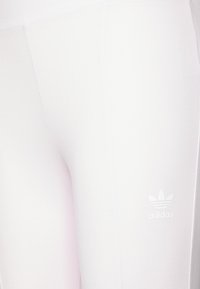 Bele legice iz raztegljivega materiala z gladko teksturo. Imajo majhen, bel Adidasov logotip na spodnji strani.
