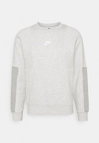 Ljusgrå sweatshirt med rund hals, gjord av mjukt tyg, med kontrasterande grå ärmar, en vit Nike-logga på bröstet och ribbade muddar.