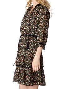 Svart blommig klänning med volangkant, som har ett knytbälte, långa ärmar och ett färgglatt mönster av små blommor och löv.