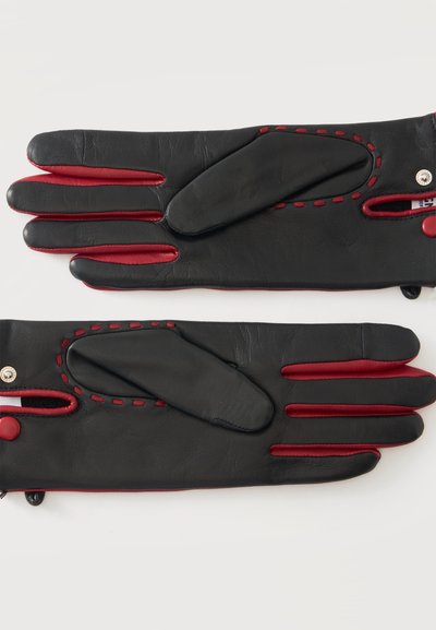 Paire de gants en cuir noir avec doublure intérieure rouge et détails de coutures rouges, posés à plat sur une surface blanche.