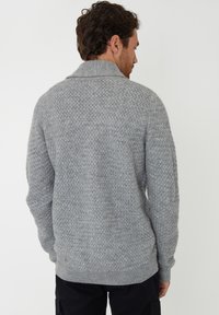 Grauer Strickpullover mit strukturiertem Muster, ausgestattet mit einem Schal-Kragen und geripptem Saum. Das Design hat einen lockeren Schnitt und lange Ärmel.