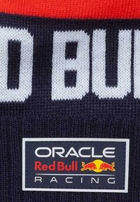 Granatowy materiał dzianinowy z wyraźnym białym napisem "RED BULL" oraz czarnym prostokątnym logo z napisami "ORACLE", "Red Bull" i akcentami graficznymi w postaci czerwonego byka.
