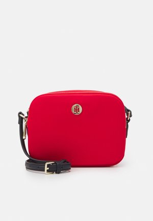 Borsa a tracolla rettangolare rossa di materiale liscio, con logo oro e tracolla nera regolabile. Chiusura con zip nella parte superiore.