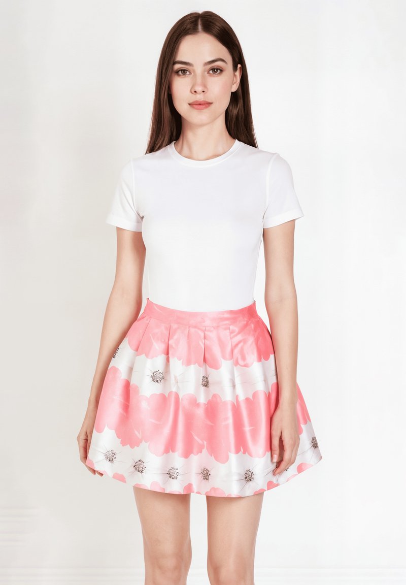 Top blanco de manga corta combinado con una falda floral rosa plisada que presenta grandes flores rosas y pequeños acentos marrones. Textura suave.