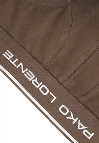 Brązowa bawełniana tkanina z białą taśmą z logo oznaczoną "Pako Lorente". Posiada gładką fakturę i prosty design z kontrastującymi detalami.