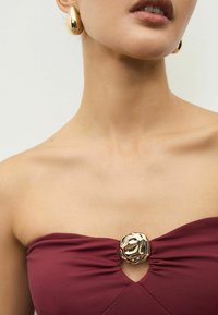 Burgundijas strapless top ar centrālu zelta metālisku akcentu; teksturēta auduma; gluda virsma; ar atslēgas caurumu.