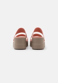 Paire de sandales à plateforme roses et beiges avec talons ouverts et deux brides, vues de dos sur fond blanc.