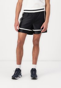 Shorts de sport noirs avec une bande blanche contrastante le long de l'ourlet et de la taille, fabriqués dans un matériau lisse et léger.