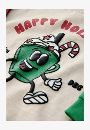 Zelená karikatura nápoje s ozdobeným kloboukem a akcentem v podobě cukrové hole. Text zní "ŠŤASTNÉ VÁNOCE." Krémové pozadí s červenými a zelenými detaily.