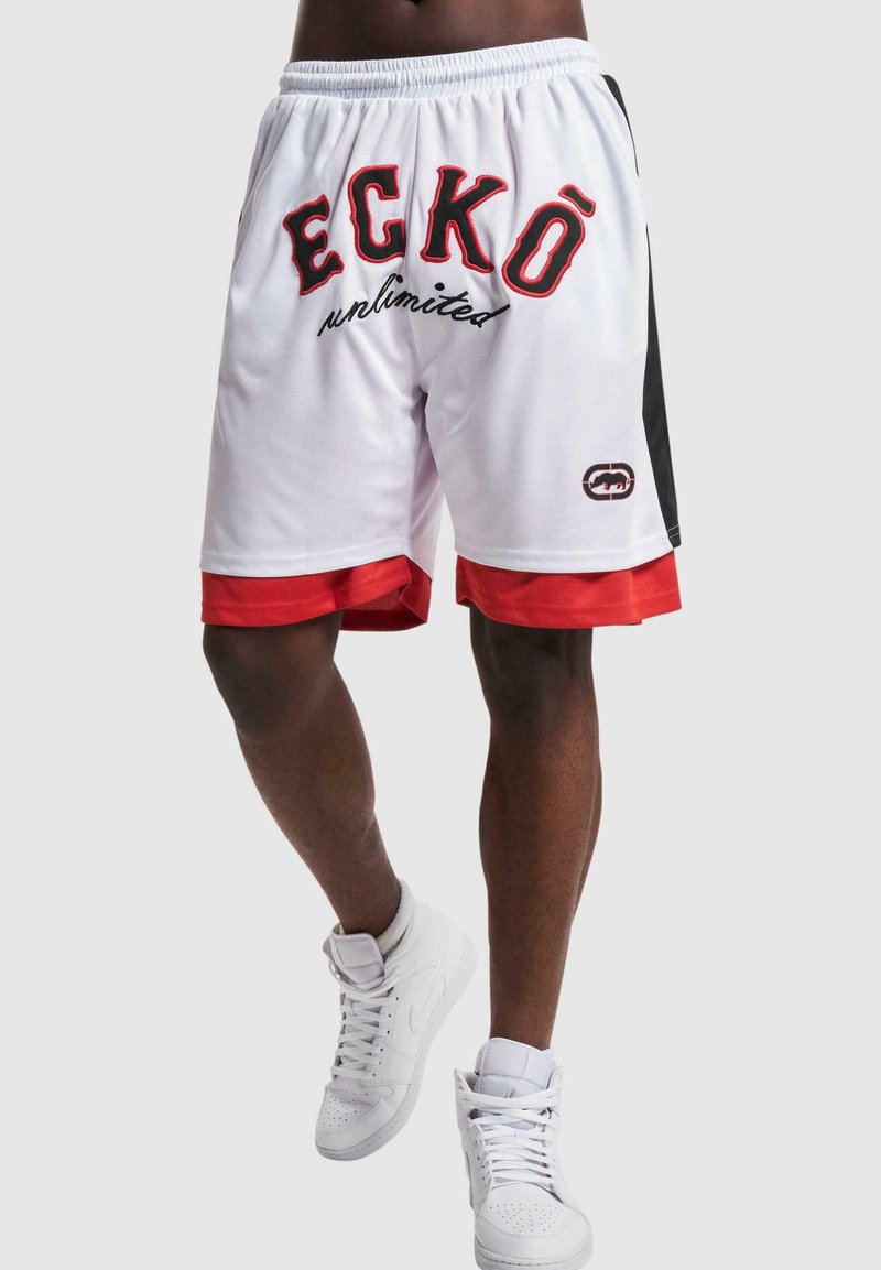 Witte sportbroekjes met zwarte en rode accenten. Bevat het "ECKŌ unlimited" logo in gedurfde zwarte en rode tekst. Glad materiaal en halverwege de dijen.