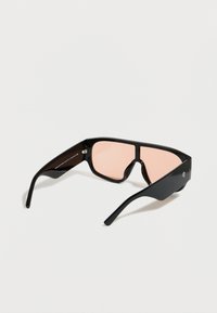 Μαύρα γυαλιά ηλίου με ορθογώνια πλαίσια και ροζ φακούς με απόχρωση. Λεπτομέρειες με υφή στα πλευρικά σκέλη. Μινιμαλιστικός σχεδιασμός χωρίς ορατά λογότυπα.
