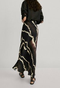 Maxi skirt in a flowing design, featuring a tie-dye pattern in dark brown and cream, with a lightweight fabric and a subtle sheen.