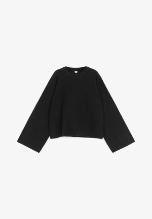 Zwarte gebreide trui met brede, lange mouwen, ronde hals en geribbelde manchetten en zoom, plat uitgespreid op een witte achtergrond.