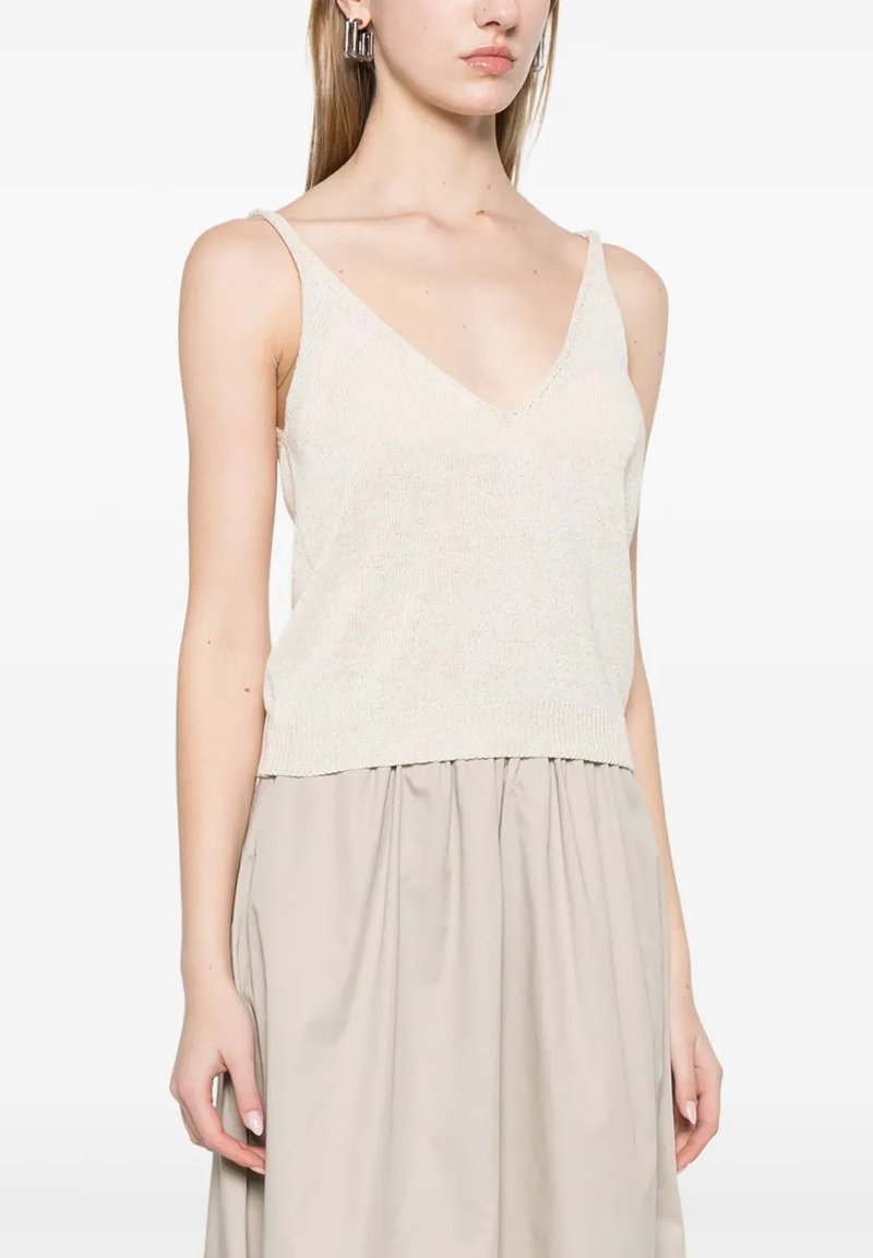 Top a maglia beige chiaro con spalline sottili, scollatura a V e orlo a coste, abbinato a una gonna fluida beige.
