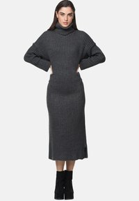 Graues, geripptes Strickkleid mit hohem Rollkragen, weiten Ärmeln und taillierter Passform. Verfügt über seitliche Schlitze am Saum für zusätzlichen Bewegungsfreiheit.