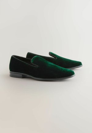 Gröna sammetsskor med slät design, rund tå, svart accenttrim och texturerad yta på en platt sula.