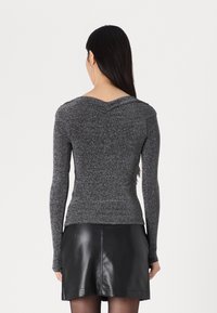 Long-sleeve top in metallic black, featuring a fitted design and v-shaped back detail. Paired with a black leather mini skirt.