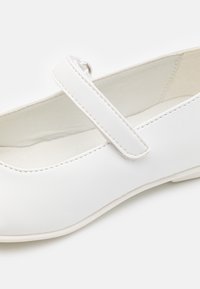 Bílé kožené boty Mary Jane s plochou podrážkou, vybavené zaoblenou špičkou a jednoduchým páskem přes vrch. Hladká textura a bezproblémový design.