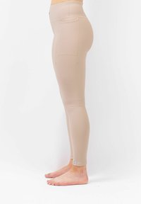 Beige leggings gemaakt van ribbelstof, met een hoge taille en achterzakken, met een strakke pasvorm en een zachte textuur.