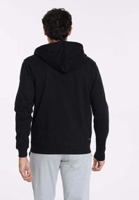 Sweat à capuche noir avec une texture douce et des poignets côtelés. Comprend une poche kangourou et un accent logo discret près de l'ourlet.