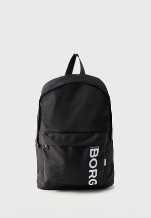 Černý batoh Björn Borg s přední kapsou na zip a svislým bílým nápisem "BORG" na kapse na jednoduchém světlém pozadí.