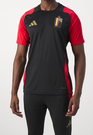 Musta ja punainen urheilupaita lyhyillä hihoilla, kultaisilla yksityiskohdilla ja Belgian vaakunalla. Valmistettu kevyestä ja hengittävästä kankaasta.