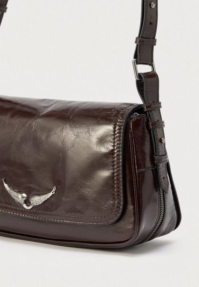 Sac bandoulière en cuir marron au design élégant, orné d'un emblème argenté en forme d'aile, avec une sangle ajustable et une fermeture zippée sur le dessus. Surface texturée.