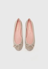 Bailarinas hechas de tela metálica beige, con punta redondeada y un detalle de lazo texturizado en la parte frontal. Forro interior en suave color rosa.
