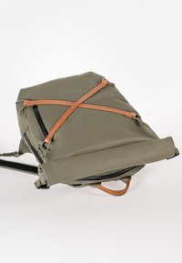 Zaino verde oliva realizzato in tessuto impermeabile con dettagli in pelle, caratterizzato da un design pieghevole unico e spallacci regolabili.