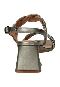 Sandalias plateadas con tacones cuadrado y tiras entrecruzadas, con una textura brillante y detalle de hebilla en el tobillo.